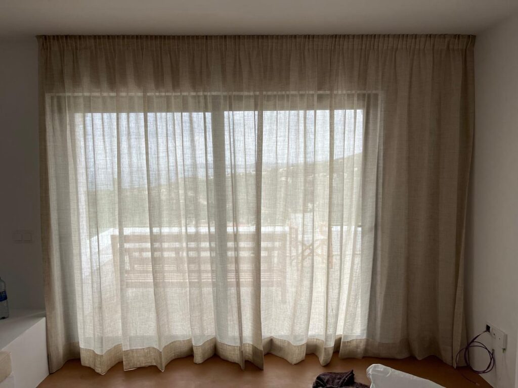 IBI HOUSE és l’empresa especialitzada en tapisseria i cortinatges de luxe que ofereix una àmplia gamma de serveis per a xalets i apartaments exclusius a Andorra i al Pirineu. Els nostres treballs de tapisseria inclouen: tapissar sofàs, butaques, cadires, capçals de llit i bancs, renovació de mobles d’autor, confecció de coixins personalitzats i fundes a mida, així com restauració de peces antigues amb acabats impecables. En el camp del cortinatge, confeccionem cortines i estors amb teixits prèmium, incorporant sistemes tècnics que permeten controlar la llum i la privacitat amb elegància. Treballem amb materials com vellut, seda, lli i altres fibres nobles, tant en dissenys clàssics com en patrons més moderns, adaptant-nos sempre a l’estil i les necessitats del client. Altres serveis que oferim inclouen la instal·lació de cortines amb sistemes domòtics, entapissats per a parets i panells decoratius, així com assessorament personalitzat en la selecció de teixits, combinacions cromàtiques i acabats per garantir una coherència total en el disseny interior. Cada projecte és únic, i en IBI HOUSE combinem artesania, tecnologia i disseny innovador per aconseguir espais exclusius, sofisticats i totalment personalitzats, garantint la màxima qualitat i un servei complet des de la concepció fins a la instal·lació final. La nostra empresa IBI HOUSE de tapisseria de luxe a Andorra fa treballs especialitzats en la confecció, restauració i instal·lació de peces tèxtils per a la decoració interior d’habitatges exclusius, xalets i apartaments prèmium. Els serveis habituals inclouen tapissar sofàs, butaques, cadires, capçals de llit i bancs amb teixits d’alta gamma, així com renovar i personalitzar mobles d’autor. També confeccionen cortines i cortinatges a mida per a grans finestrals i sistemes de control solar, utilitzant materials nobles com el vellut, la seda, el lli i altres teixits selectes. (De les millors fàbriques de teixits per a decoració d’Itàlia) Entre els treballs més sol·licitats s’inclouen: Tapisseria de sofàs, butaques, cadires i mobles d’autor. Elaboració de cortines, estors i cortinatges a mida amb disseny exclusiu. Confecció de coixins decoratius, fundes i accessoris tèxtils personalitzats. Renovació de capçals de llit, banquetes i mobles auxiliars. Instal·lació de cortines tècniques i sistemes domòtics per control solar. Utilització de teixits prèmium amb varietat de textures, colors i estampats. Serveis de restauració per peces antigues o de gran valor artístic. Projectes integrals per xalets, apartaments, hotels i boutiques i cases de luxe. Disseny i confecció d’entapissats per parets i panells decoratius. Assessorament personalitzat per seleccionar materials, acabats i combinacions òptimes. A més, la nostra empresa especialitzada en cortinatges de luxe i ens encarreguem de crear solucions a mesura que aporten elegància, funcionalitat i exclusivitat a qualsevol espai, dissenyant cortines i entapissats que s’adapten a les tendències actuals, les demandes del client i l’estil arquitectònic de cada projecte.