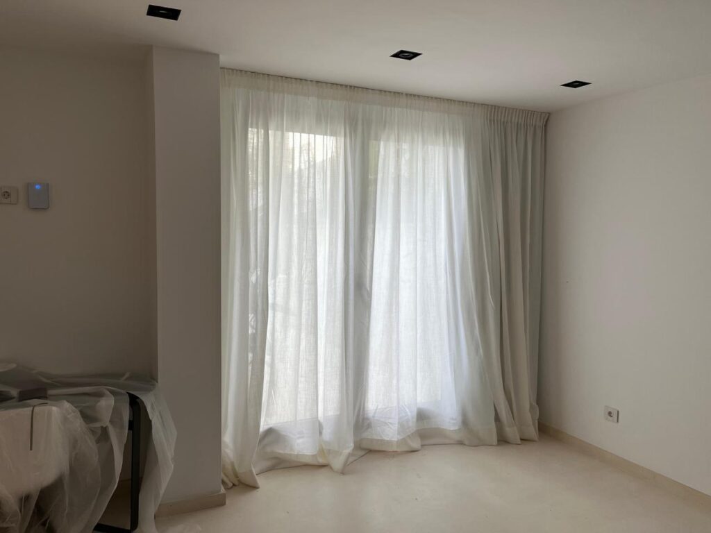 IBI HOUSE és l’empresa especialitzada en tapisseria i cortinatges de luxe que ofereix una àmplia gamma de serveis per a xalets i apartaments exclusius a Andorra i al Pirineu. Els nostres treballs de tapisseria inclouen: tapissar sofàs, butaques, cadires, capçals de llit i bancs, renovació de mobles d’autor, confecció de coixins personalitzats i fundes a mida, així com restauració de peces antigues amb acabats impecables. En el camp del cortinatge, confeccionem cortines i estors amb teixits prèmium, incorporant sistemes tècnics que permeten controlar la llum i la privacitat amb elegància. Treballem amb materials com vellut, seda, lli i altres fibres nobles, tant en dissenys clàssics com en patrons més moderns, adaptant-nos sempre a l’estil i les necessitats del client. Altres serveis que oferim inclouen la instal·lació de cortines amb sistemes domòtics, entapissats per a parets i panells decoratius, així com assessorament personalitzat en la selecció de teixits, combinacions cromàtiques i acabats per garantir una coherència total en el disseny interior. Cada projecte és únic, i en IBI HOUSE combinem artesania, tecnologia i disseny innovador per aconseguir espais exclusius, sofisticats i totalment personalitzats, garantint la màxima qualitat i un servei complet des de la concepció fins a la instal·lació final. La nostra empresa IBI HOUSE de tapisseria de luxe a Andorra fa treballs especialitzats en la confecció, restauració i instal·lació de peces tèxtils per a la decoració interior d’habitatges exclusius, xalets i apartaments prèmium. Els serveis habituals inclouen tapissar sofàs, butaques, cadires, capçals de llit i bancs amb teixits d’alta gamma, així com renovar i personalitzar mobles d’autor. També confeccionen cortines i cortinatges a mida per a grans finestrals i sistemes de control solar, utilitzant materials nobles com el vellut, la seda, el lli i altres teixits selectes. (De les millors fàbriques de teixits per a decoració d’Itàlia) Entre els treballs més sol·licitats s’inclouen: Tapisseria de sofàs, butaques, cadires i mobles d’autor. Elaboració de cortines, estors i cortinatges a mida amb disseny exclusiu. Confecció de coixins decoratius, fundes i accessoris tèxtils personalitzats. Renovació de capçals de llit, banquetes i mobles auxiliars. Instal·lació de cortines tècniques i sistemes domòtics per control solar. Utilització de teixits prèmium amb varietat de textures, colors i estampats. Serveis de restauració per peces antigues o de gran valor artístic. Projectes integrals per xalets, apartaments, hotels i boutiques i cases de luxe. Disseny i confecció d’entapissats per parets i panells decoratius. Assessorament personalitzat per seleccionar materials, acabats i combinacions òptimes. A més, la nostra empresa especialitzada en cortinatges de luxe i ens encarreguem de crear solucions a mesura que aporten elegància, funcionalitat i exclusivitat a qualsevol espai, dissenyant cortines i entapissats que s’adapten a les tendències actuals, les demandes del client i l’estil arquitectònic de cada projecte.